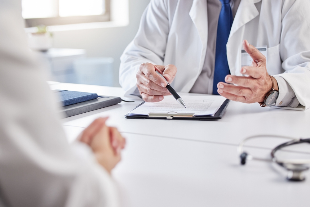 Médico e paciente a rever relatório clínico em consulta para perícia médica